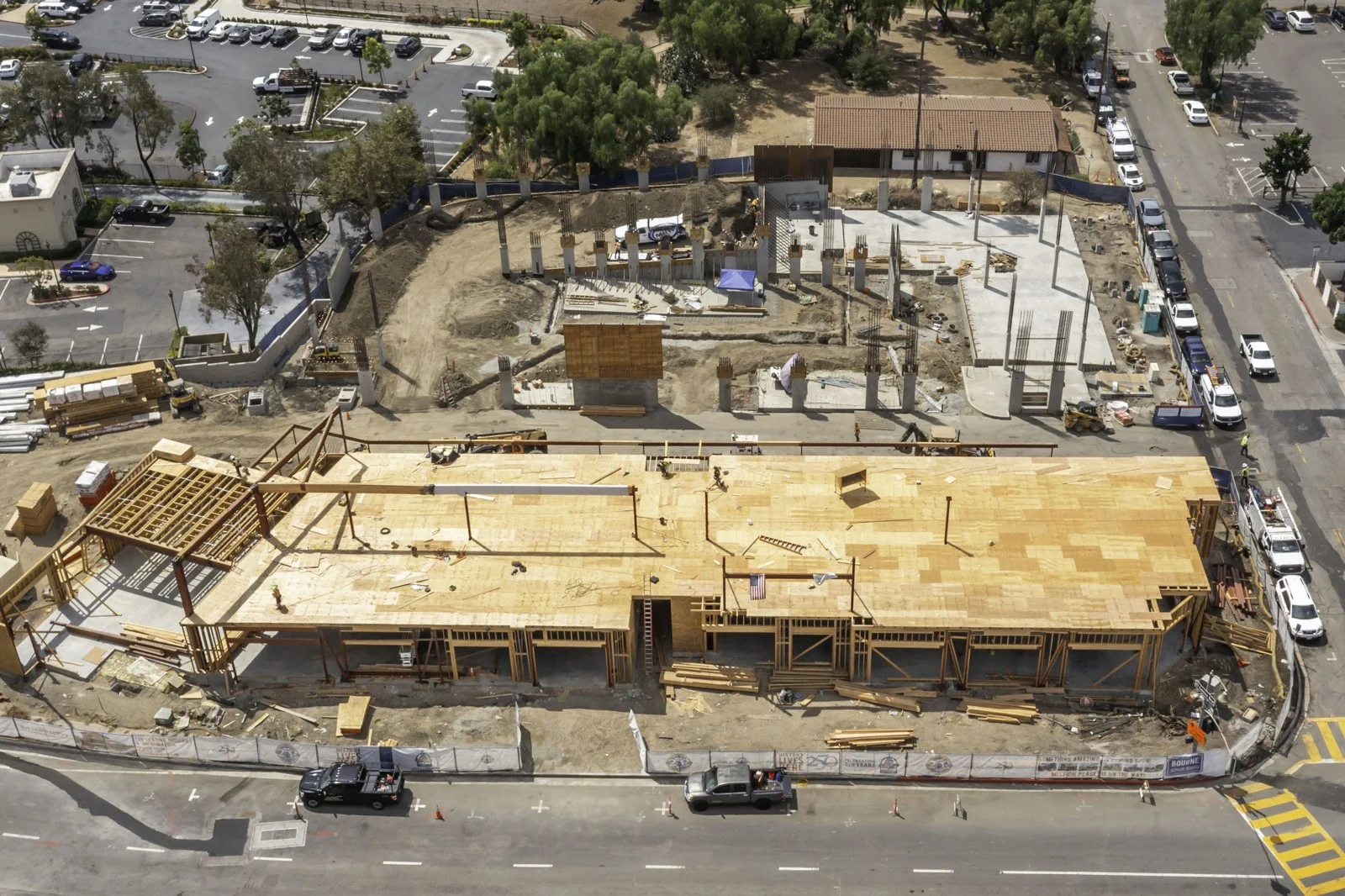 Broad plywood deck with exposed steel members above it and concrete columns with reinforcing steel farther across the Mission Place site.