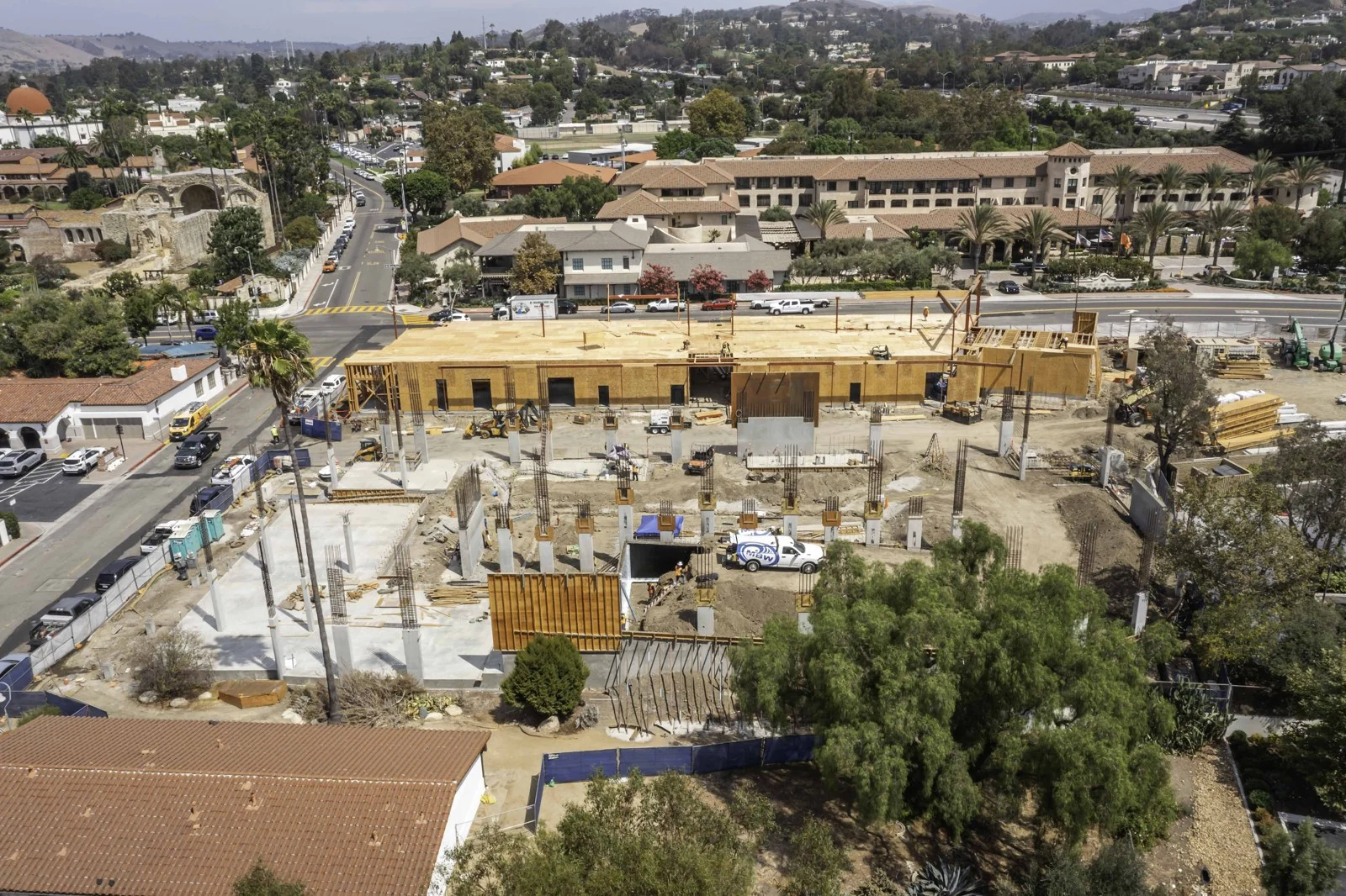 Elevated overview of Mission Place with concrete slabs, reinforcing-steel cages, wood-sheathed walls, diagonal braces and perimeter screening.